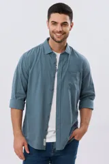 Camisa de lino de manga larga en color beige, con cuello camisero, cierre frontal de botones y un bolsillo ojal en el pecho.