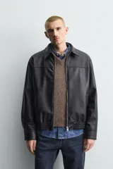 Cazadora bomber de efecto piel color marrón oscuro, con cuello solapa, cierre frontal de cremallera, bolsillos de vivo en cadera y bajo elástico.