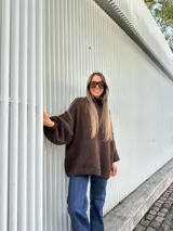 Buzo de punto oversize color chocolate, con cuello alto, mangas largas abullonadas y detalles de costuras bordadas a mano en color blanco en las uniones de las mangas.