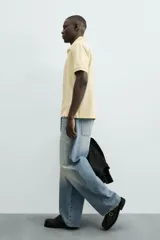 Jeans de hombre, corte balloon fit, tiro medio, confeccionados en denim rígido de algodón. Presentan un efecto lavado con un marcado degradado vertical, cinco bolsillos y cierre frontal con cremallera y botón.