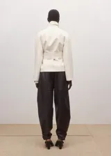 Chaqueta de mezcla de lana y poliéster color marfil, con solapas de muesca, cuello alto drapeado superpuesto y cierre cruzado con lazo ajustable del mismo tejido en la cintura.