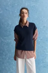 Chaleco de tejido de punto color beige claro, con cuello redondo y diseño de líneas limpias con hombros caídos y terminaciones acanaladas.