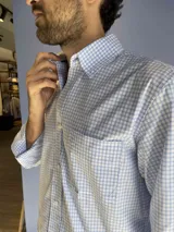 Camisa de corte clásico con estampado de cuadros en tonos rosados y celestes, con cuello abotonado, manga larga y bolsillo frontal con detalle bordado.