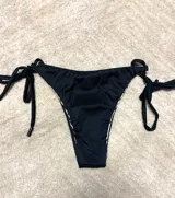Pantie de bikini negro con tiras laterales ajustables.