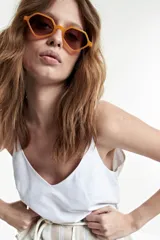 Lentes de sol con marco geométrico color naranja y lentes marrones.