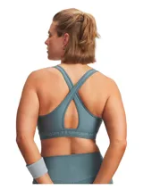 Top deportivo Under Armour de soporte medio, confeccionado en tejido HeatGear de doble capa. Presenta diseño de espalda cruzada, banda elástica inferior con logo de la marca y copas extraíbles con perforaciones para mayor transpirabilidad.