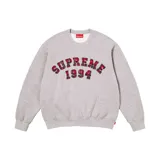 Buzo de cuello redondo Supreme en color gris melange, con diseño de letras y números aplicados en tela escocesa roja y azul con bordes deshilachados.