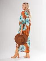 Vestido camisero largo con estampado floral en tonos rojos y negros, con cuello camisero, abotonadura frontal y mangas largas con puños abotonados.