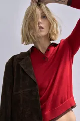 Jersey de punto de manga larga con cuello polo y cierre frontal de botones. Presenta un diseño de contraste en el cuello, los puños y el ruedo.