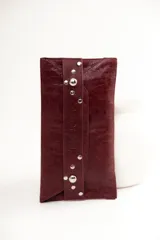 Sobre de cuero color bordó con cierre de solapa con botón a presión y tachas plateadas.