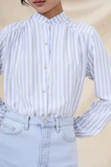 Camisa de manga larga con cuello mao y estampado a rayas verticales celestes y blancas.