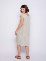 Vestido corto de viscosa con estampado a rayas verticales en tonos celeste, azul y blanco. Sin mangas, con volados en los hombros y escote cuadrado con ribete azul marino.