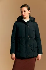 Campera puffer beige con capucha desmontable, cordón ajustable en la cintura, bolsillos laterales y cierre frontal con botones y cremallera.
