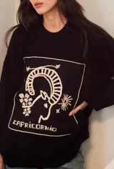 Sweater de punto oversize color crudo, con cuello redondo y diseño bordado a mano en el frente representando al signo Cáncer con un cangrejo, un corazón y una estrella.