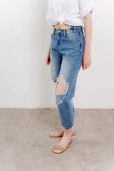 Jean azul de tiro medio y calce relaxed, con roturas amplias y desflecadas.