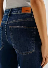 Pantalón de jean de corte flare con tiro medio y lavado claro. Presenta diseño de cinco bolsillos, cierre frontal con botón y costuras reforzadas.