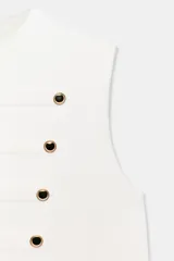 Chaleco blanco de cuello redondo y sin mangas, con diseño de doble botonadura ornamental con botones dorados y cierre frontal con corchetes ocultos.