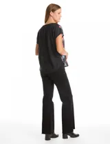 Remera de manga corta con frente estampado con diseño floral multicolor sobre fondo negro y espalda lisa. Presenta cuello redondo a la base y corte recto.