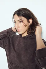 Buzo canguro color marrón oscuro con efecto lavado, calce relajado, capucha integrada, bolsillo frontal tipo canguro y terminaciones clásicas en puños y ruedo.