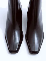 Bota de caña media confeccionada en cuero negro, con punta cuadrada y taco ancho de altura media.