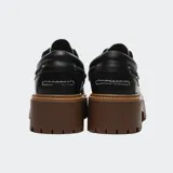 Zapatos tipo náutico Timberland con plataforma dentada color marrón. El cuerpo es de cuero negro con detalles de ojalillos metálicos y un panel superior con estampado animal print texturizado.