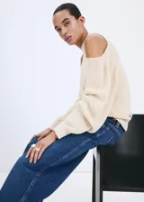 Jersey de punto color crudo, de diseño fluido con cuello redondo, hombros descubiertos y mangas abullonadas.