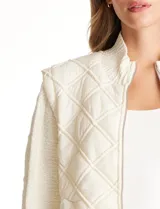 Campera combinada Current Air, con torso acolchado en diseño de rombos y mangas de tejido de punto grueso con diseño de ochos. Presenta cierre frontal metálico, cuello alto y puños y ruedo acanalados.