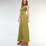 Mono color verde oliva, compuesto por pantalón palazzo de tiro alto y chaleco con escote en V cruzado, cierre lateral con botón y solapa decorativa.