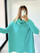 Polerón de punto color verde agua, con diseño mega oversize y cuello caído tipo polera. Presenta mangas largas con puños acanalados.