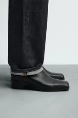 Bota de piel negra con cierre de cremallera lateral, horma cuadrada y tacón de 5 cm.