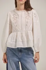 Blusa de algodón color blanco con diseño romántico, cuello redondo, mangas largas abullonadas con puños elásticos y detalles de bordado inglés y encaje en el frente y hombros.