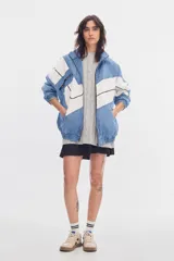 Campera deportiva de denim soft con diseño de bloques en tonos azul y blanco, cuello alto, cierre frontal y bolsillos delanteros. Corte oversized con cintura y puños elásticos.