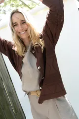 Cardigan de punto color marrón, abierto con botones imitación hueso, manga larga con parche bordado y diseño texturado.