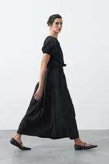 Falda larga plisada color marrón, de silueta amplia y caída fluida.