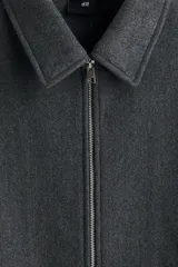 Sobrecamisa de fieltro color gris oscuro, con cuello, cierre bidireccional y bolsillos insertados en la parte delantera. Presenta un corte estándar y no tiene forro.