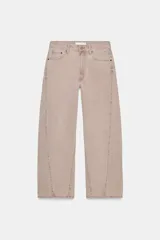 Jeans de tiro medio, color beige rosado con efecto lavado, corte amplio (baggy balloon) y detalle de costuras torcidas en el frente de las piernas.