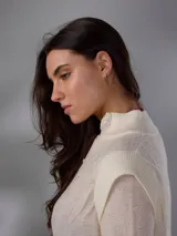 Saco largo de punto color blanco, confeccionado en 100% lana merino natural, con diseño jacquard de ramas, cuello alto, cierre frontal con pequeños botones y aberturas laterales.