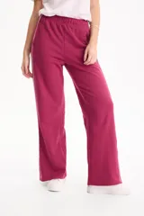 Pantalón deportivo negro de corte wide leg, sin frisa, con ribete blanco en los laterales y aberturas con botones en los tobillos.