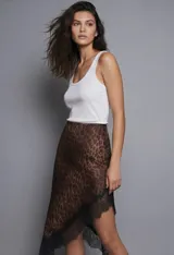 Falda midi de seda con estampado animal print de leopardo en tonos marrones y negros. El ruedo es asimétrico y está terminado con un borde de encaje negro.