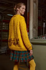 Sweater de lana amarillo con aplique circular de lana marrón en el frente. Corte holgado, cuello redondo y puños acanalados. 