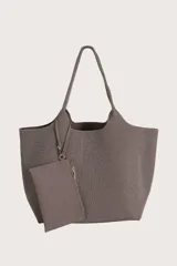 Bolso tipo tote de tejido de punto acanalado en color marrón, con diseño amplio y asas integradas. Incluye un pequeño neceser extraíble con cierre, sujeto al bolso mediante una tira.