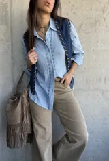 Camisa celeste de manga larga con bordados geométricos frontales a lo largo de la botonadura, cuello camisero clásico y cierre frontal de botones.