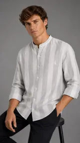 Camisa de lino con diseño de rayas anchas en tonos blanco y gris, cuello mao y mangas largas con puños arremangados.