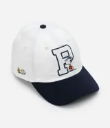 Gorra blanca de sarga con visera azul marino y bordado de Snoopy jugando baseball.