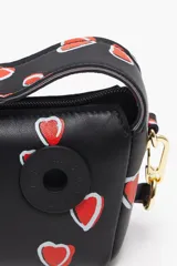 Bolso bandolera negro con estampado de corazones rojos, de tamaño mini, con cierre de cremallera y asa de mano.