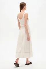 Vestido midi de lino color blanco con cuello cuadrado, sin mangas, detalle de pespuntes a contratono y cinturón con hebilla integrada en la cintura.