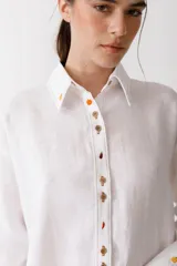 Camisa blanca de lino con botones de carey con forma de frutas, manga larga y bolsillo de parche en el pecho.