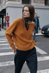 Jersey de punto color naranja quemado, de manga larga y cuello redondo. Presenta un detalle de nudo en la espalda.