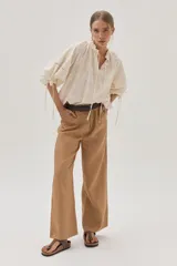 Blusa color crudo con bordado calado, cuello con volantes y lazos para ajustar. Mangas abullonadas con puños elásticos y lazos.