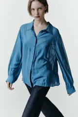 Camisa de manga larga con cuello solapa, confeccionada en tejido fluido. Presenta detalle de jaretas verticales en el frente y cierre frontal con botones forrados al tono.